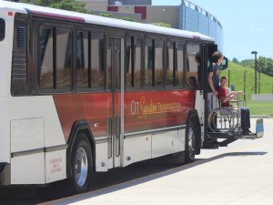 Two people getting off of a white and red CIT Signature Transportation Transit Bus