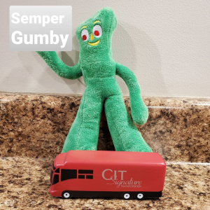 Semper Gumby doll on a counter with a mini red bus