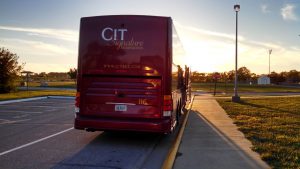 Red CIT Signature Transportation coach bus in a parking lot during sunset